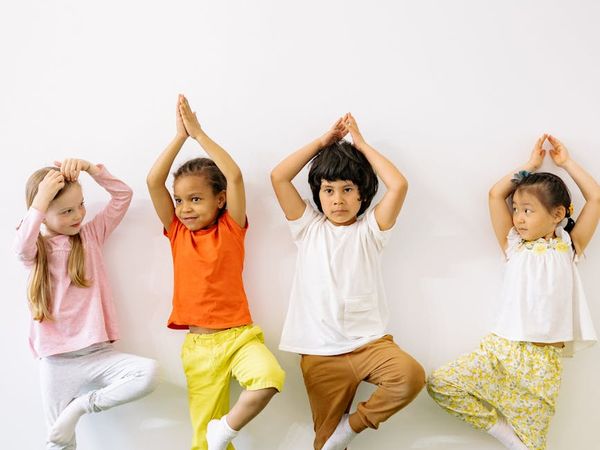 Child stretching in a happy yoga pose with sunshine.